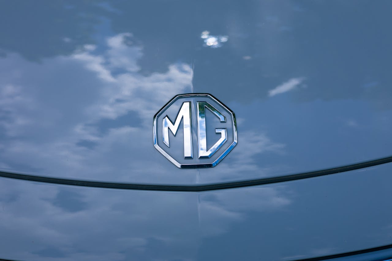 The Art of Drawing Readers In: Your attractive post title goes here Vibrant MG logo on a car hood with striking sky reflection, symbolizing elegance.